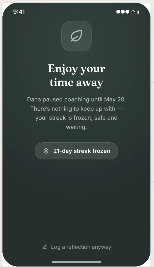 A client phone screen reading "Enjoy your time away. Dana paused coaching until May 20. There's nothing to keep up with, your streak is frozen, safe and waiting." with a "21-day streak frozen" badge and a quiet "Log a reflection anyway" link at the bottom.